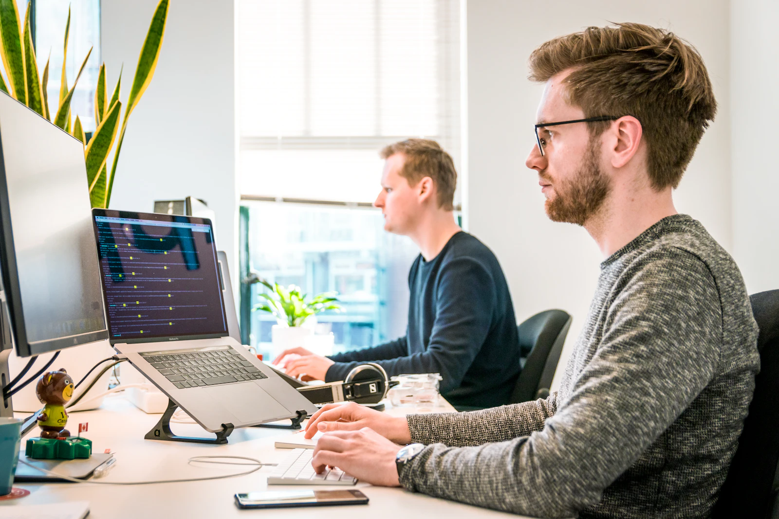 A team working at separate desks in a dim office, each screen its own pool of light
